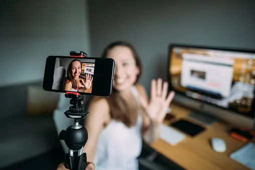 A lady holding her mobile phone and appears to be vlogging