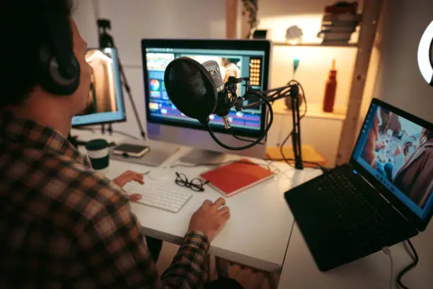 Man on his desk in front of a computer monitor with a big microphone