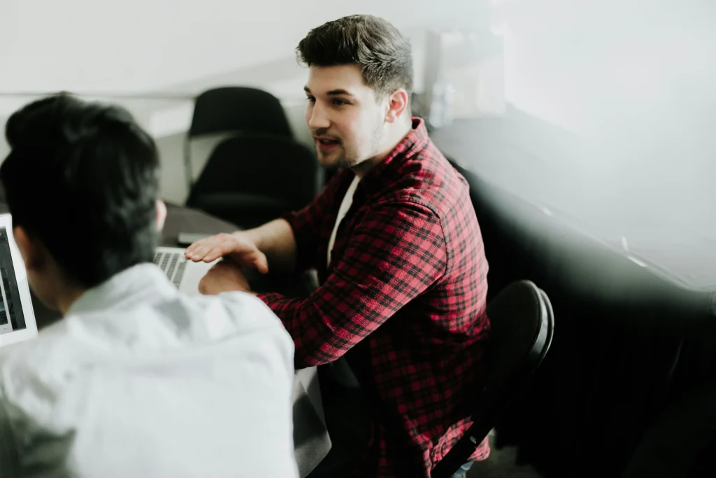 The man is looking at and listening to another man who is probably explaining something