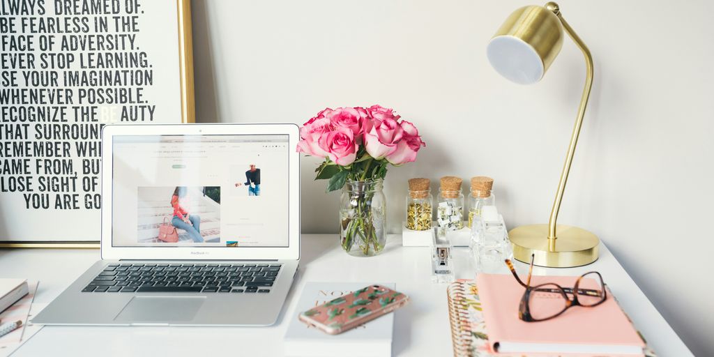 Pink flowers and a Gold lamp beside a laptop