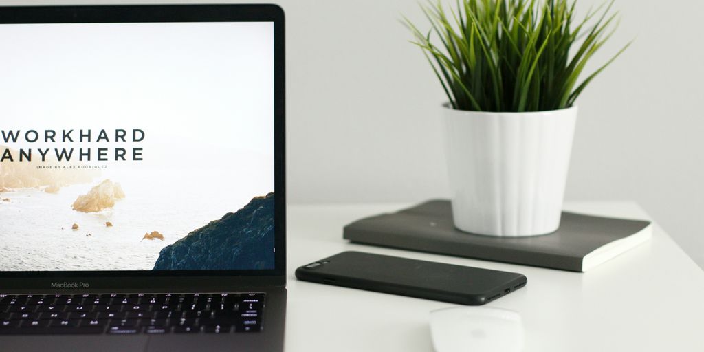 A Black laptop, mobile phone, and notebook on a desk