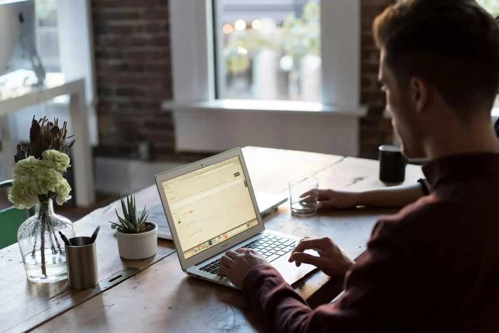 A man working on a laptop at a cozy workspace, possibly remote or freelance work.