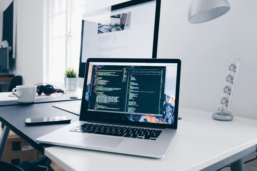 A laptop displaying code on a desk in a modern workspace.