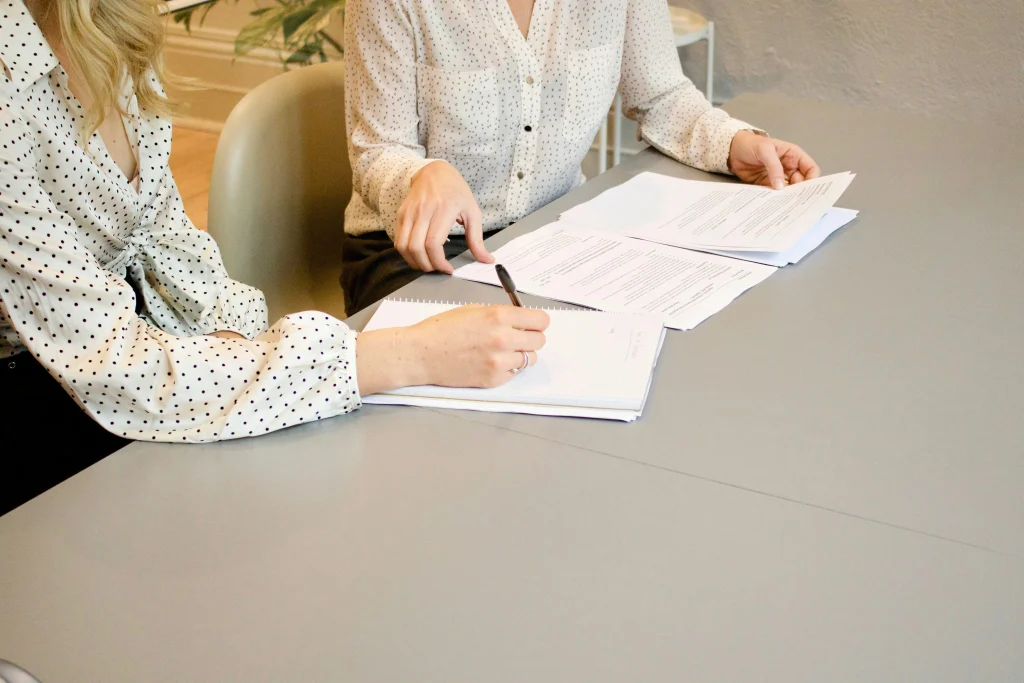 Two individuals reviewing and editing legal documents at a desk.