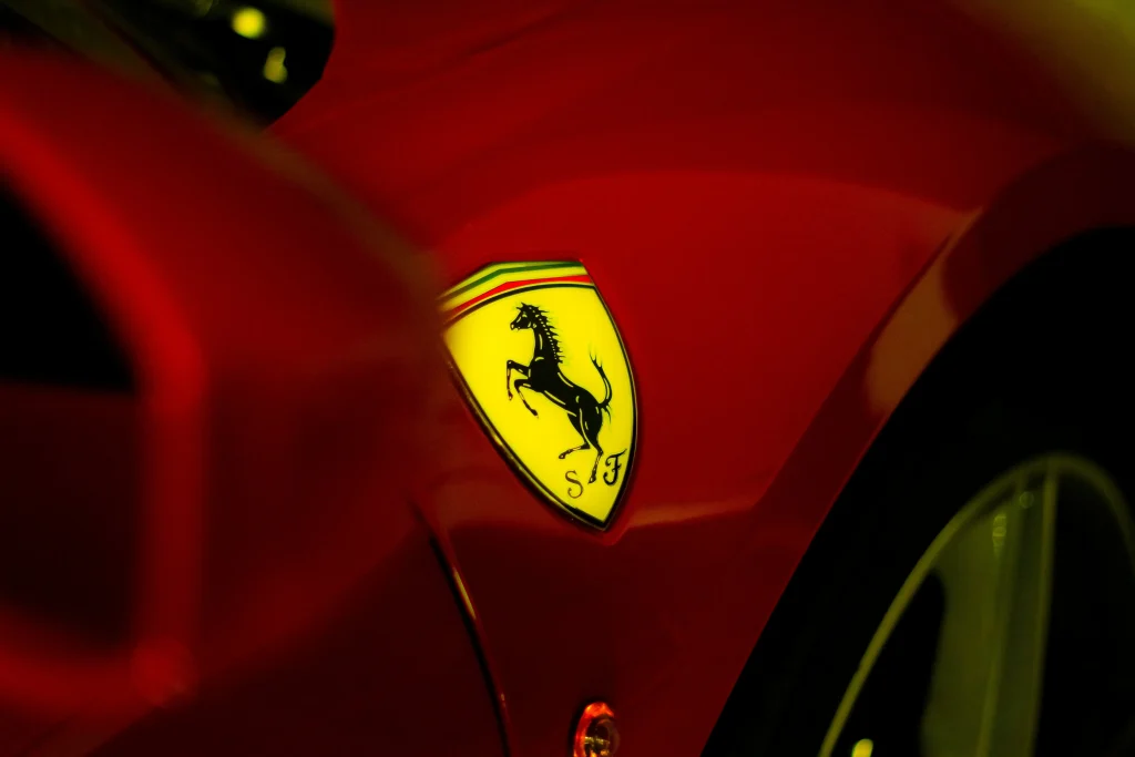 A close-up view of a Ferrari logo on a bright red car, showcasing luxury and brand identity.