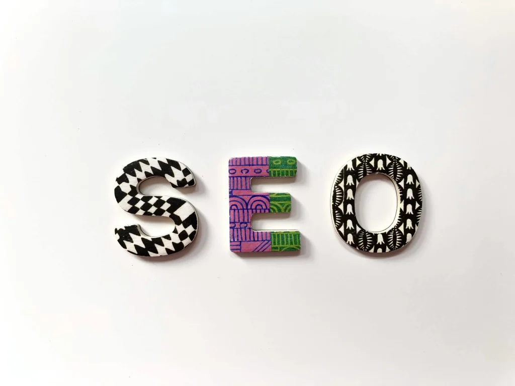 The letters "SEO" are arranged in a decorative style, each letter featuring unique patterns and colors against a plain white background