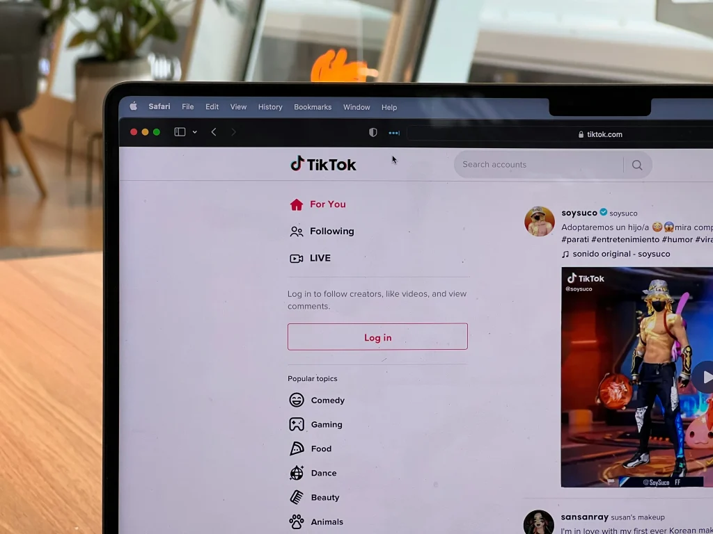 A laptop screen shows TikTok's "For You" page with popular topics and a video preview in a casual workspace setting.