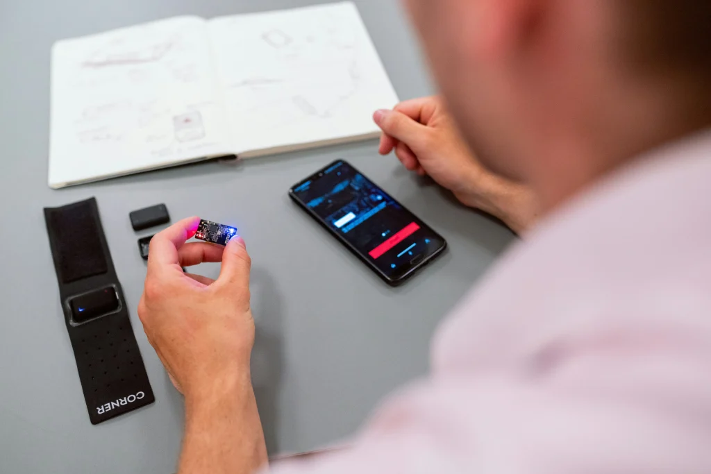 A person testing and developing wearable tech or IoT devices with a smartphone interface.